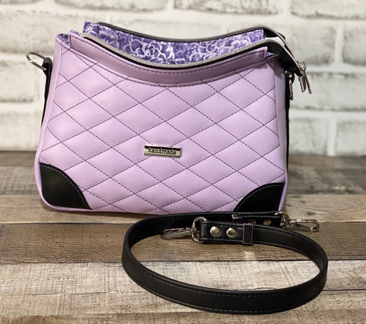 Quilted lilac purple handbag with black accents showing what the bag looks like open.