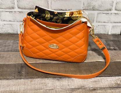 Orange quilted handbag with gold hardware. Showing open zipper
