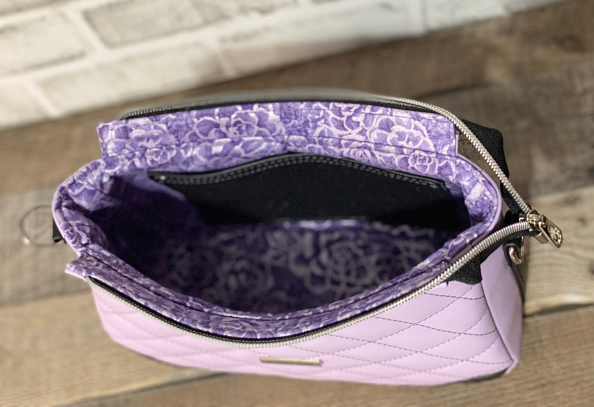 Quilted lilac purple handbag with black accents. Inside view of the bag. 
