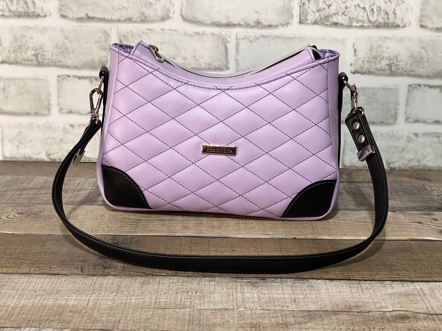 Quilted lilac purple handbag with black accents.Front view
