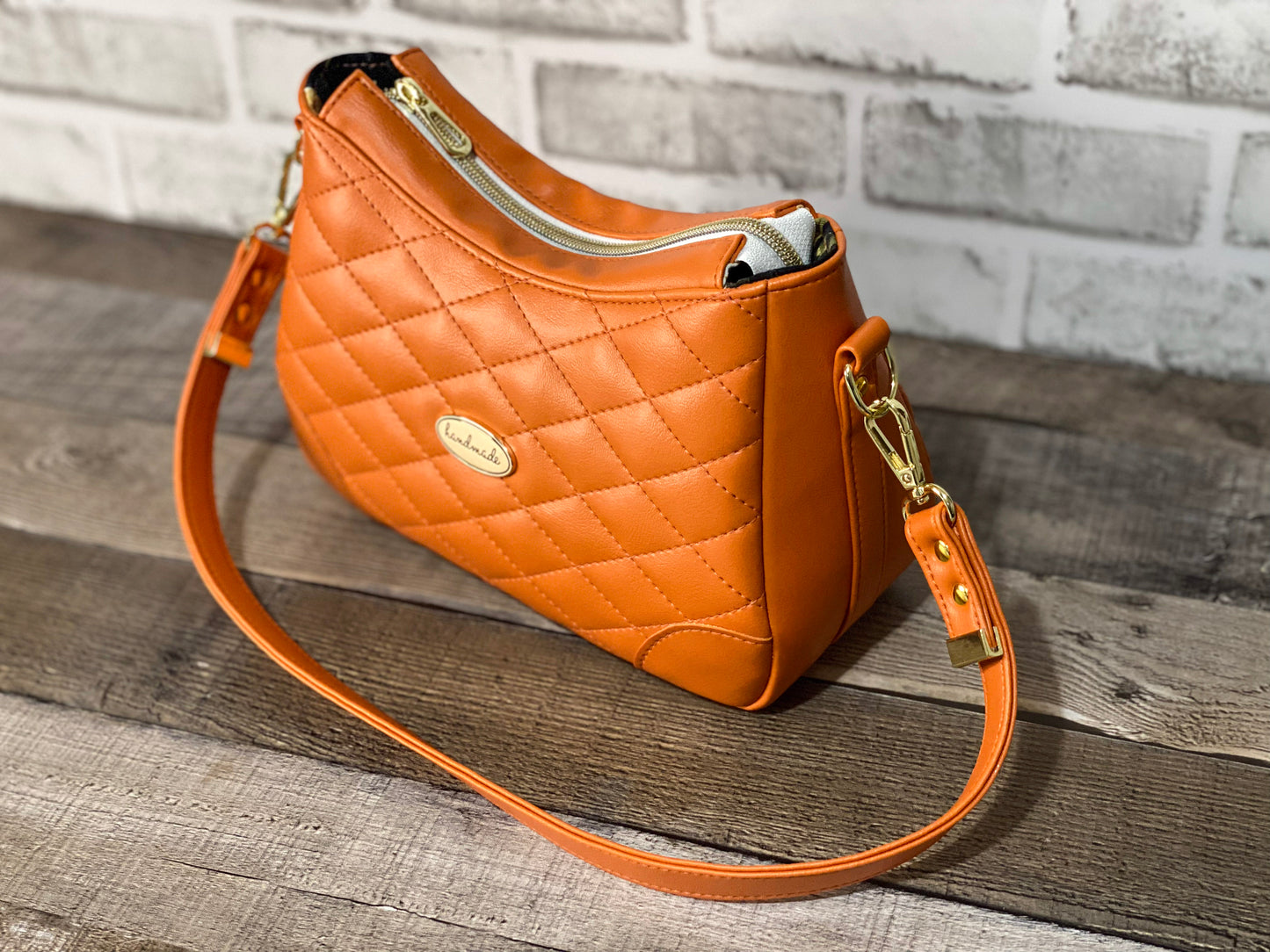 Orange quilted handbag with gold hardware. Side view