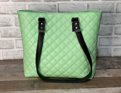 Mint green quilted handbag with black straps. Back View
