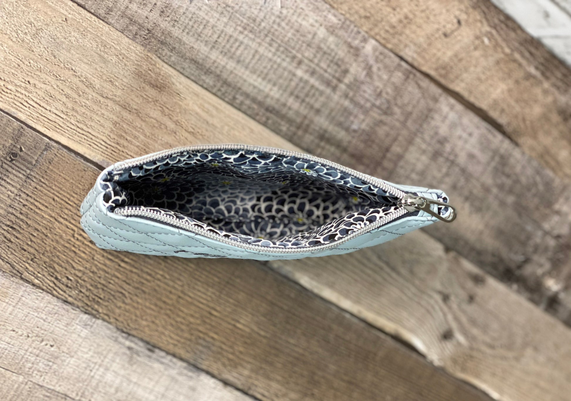 inside lining with grey flowers to baby blue quilted pouch. 