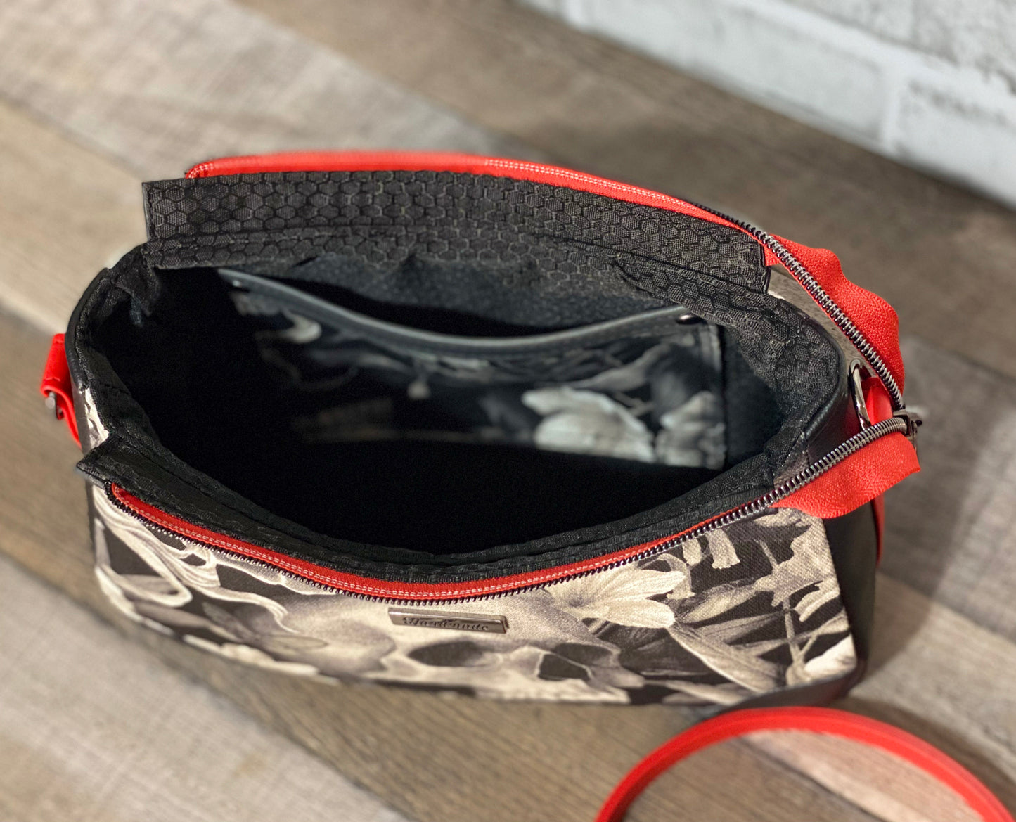 Handbag with skull and floral design with black and red faux leather accents.  Inside view.