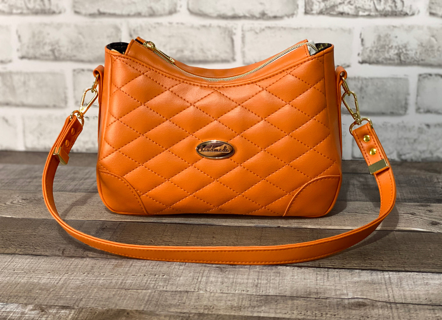 Orange quilted handbag with gold hardware. Front view