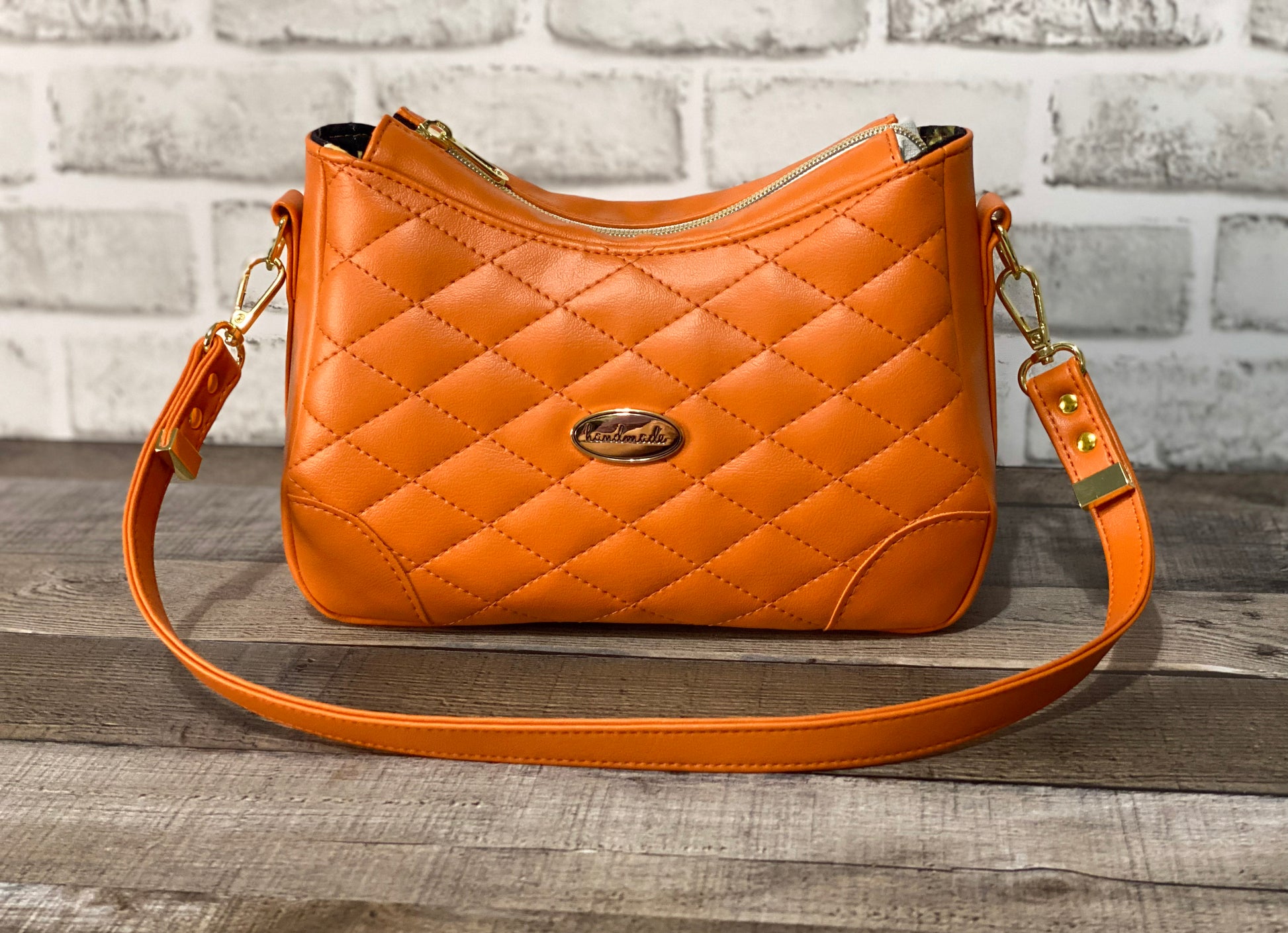 Orange quilted handbag with gold hardware. Front view