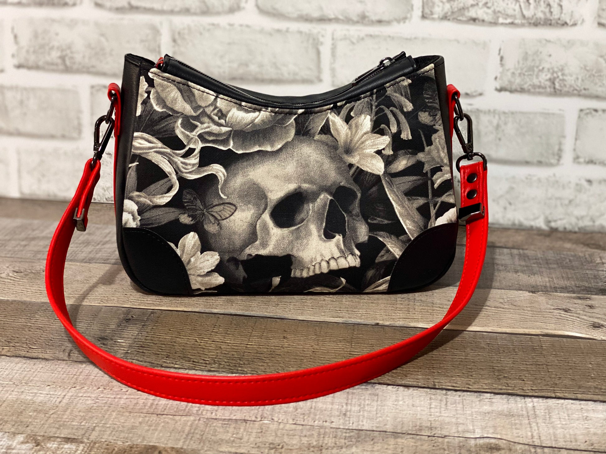 Handbag with skull and floral design with black and red faux leather accents.  Back view.