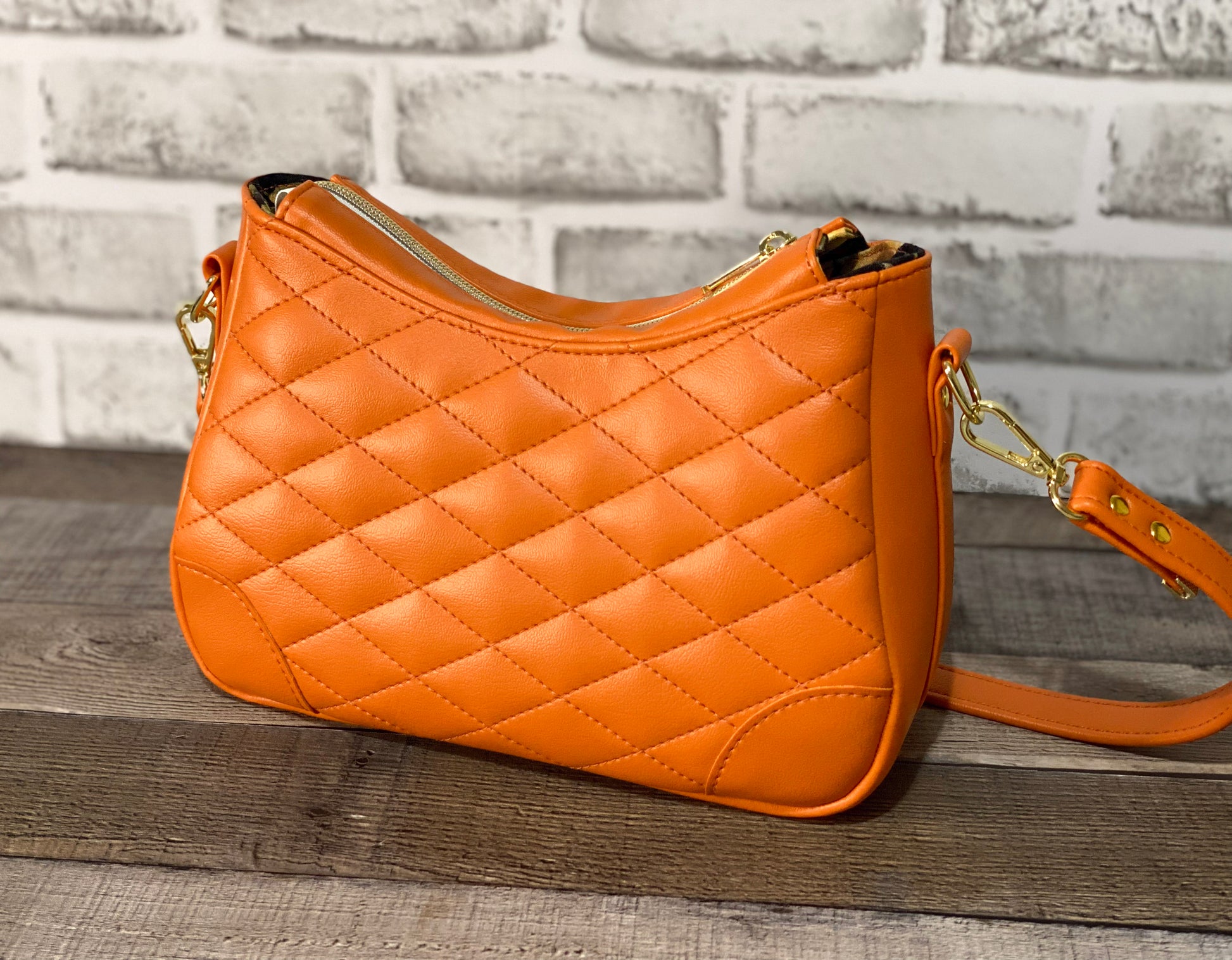 Orange quilted handbag with gold hardware. Back view.