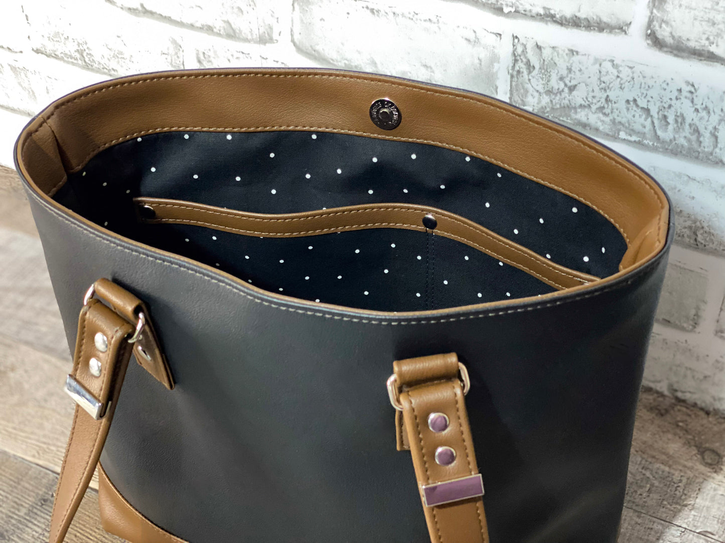 Black leather handbag with brown straps showing lining and double slip pocket. 