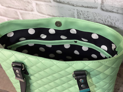 Mint green quilted handbag with black straps with black and white polkadot cotton lining with double slip pocket. 