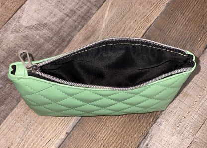 Black lining to mint green quilted pouch.