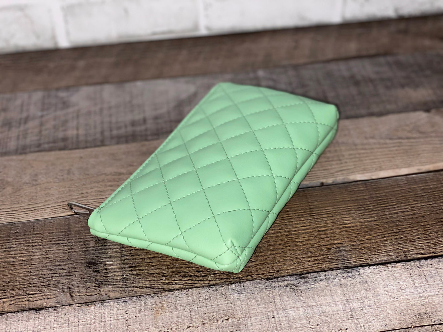 Side view of mint green quilted pouch.