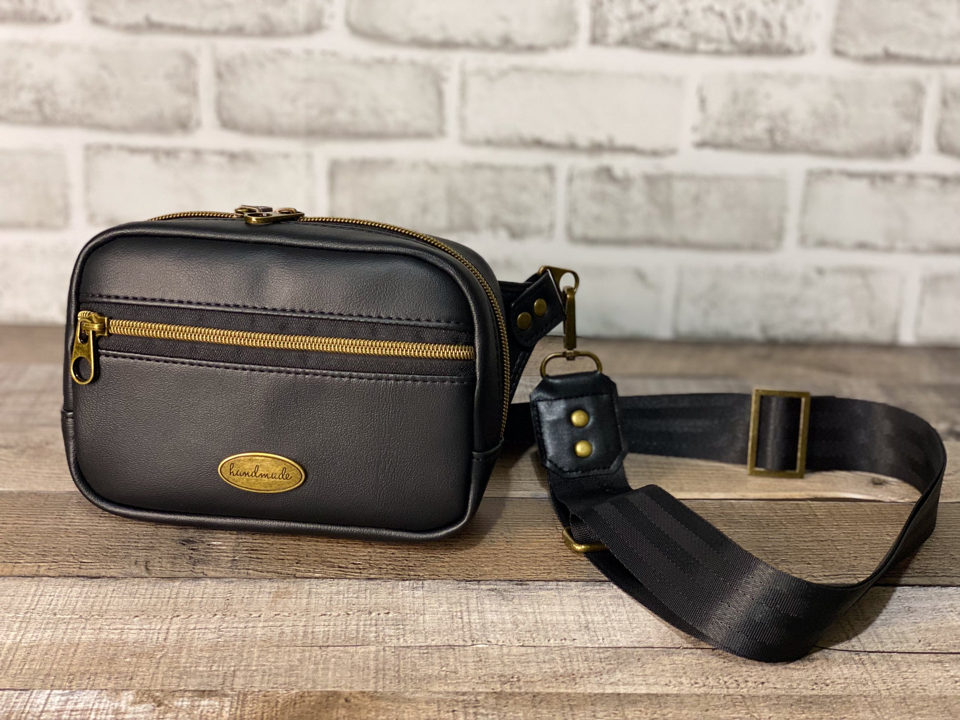 Black hip bag or can be used as a crossbody. Antique gold hardware front panel with strap. 