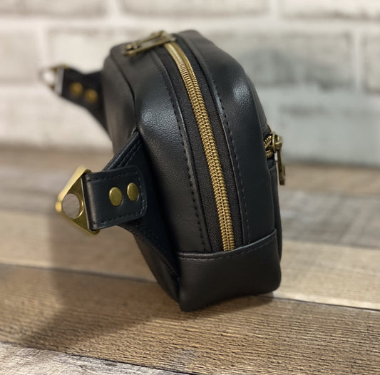 Side view of black faux leather hip back with antique gold hardware. 