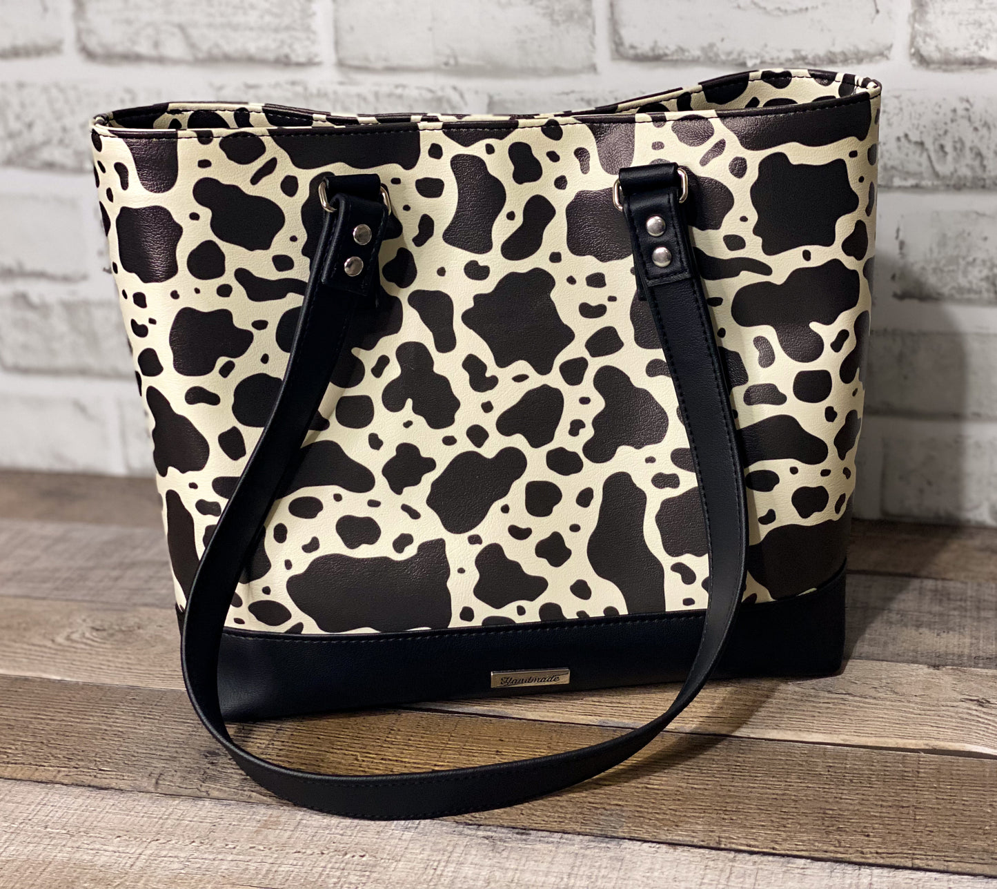 Black and white cow print big b tote bag front panel. 
