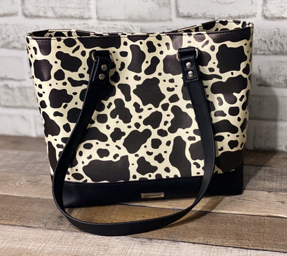 Black and white cow print big b tote bag front panel. 