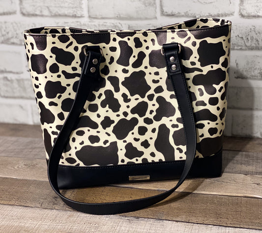 Black and white cow print big b tote bag front panel. 