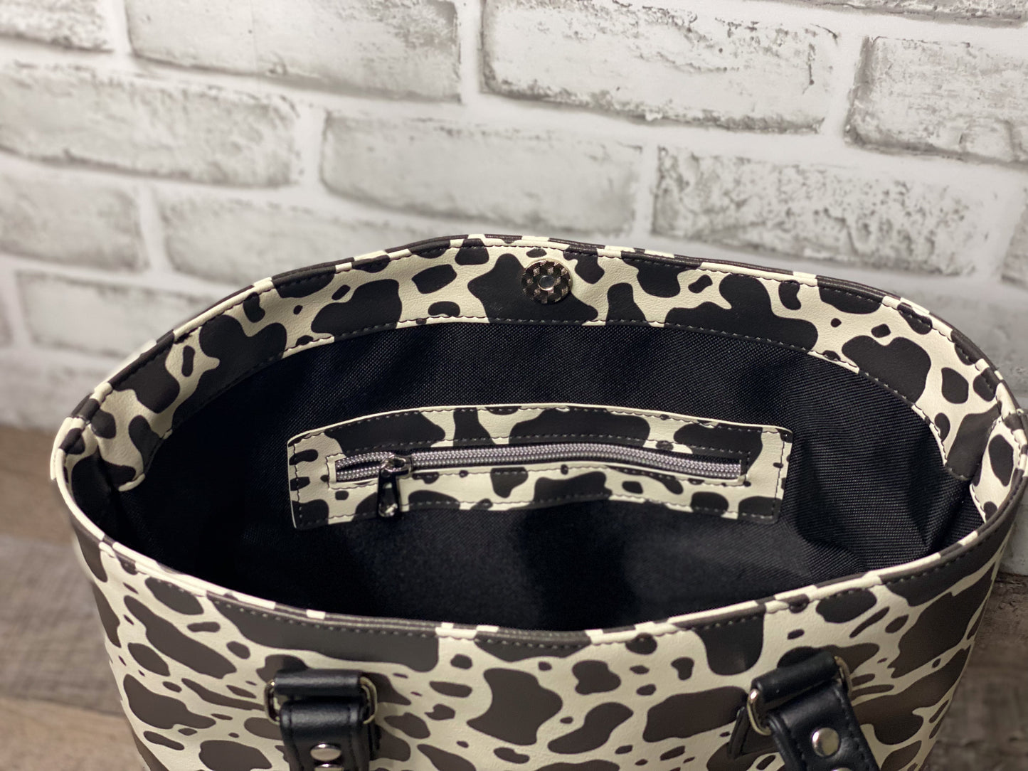 Black and white cow print big b tote bag interior showing cow print zipper overlay. 