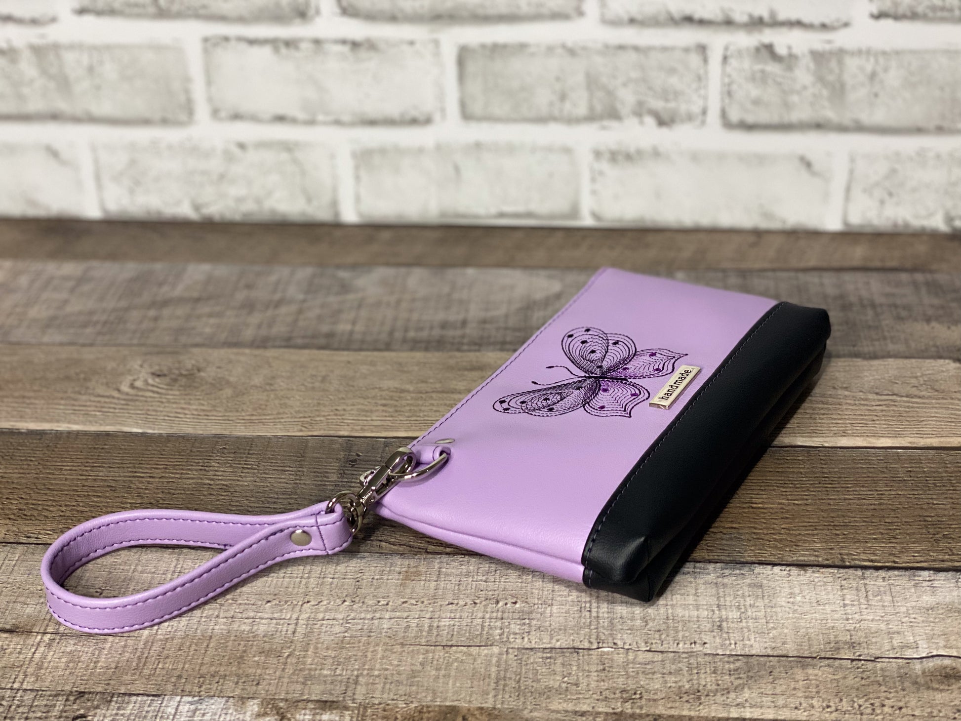 Lilac wristlet with embroidered butterfly side and bottom view. 