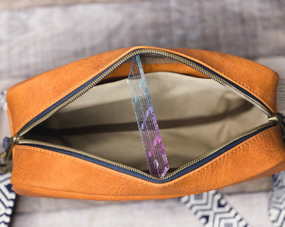 Rust orange crossbody bag with navy blue and white webbing for the strap. Showing the inside slip pocket with khaki canvas lining. 