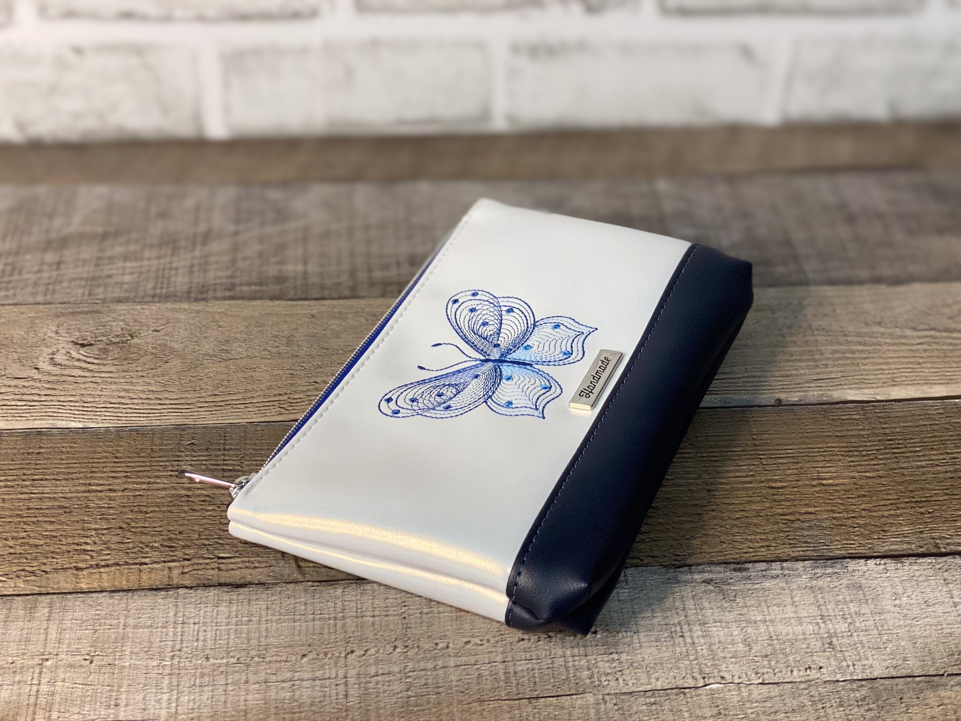 White pouch with blue butterfly design on a wooden surface