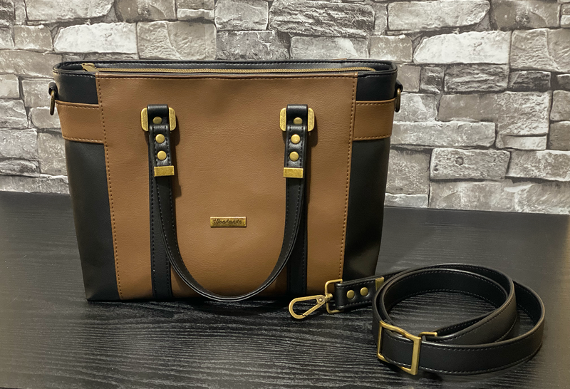 Brown faux leather bag with black accents and straps. 