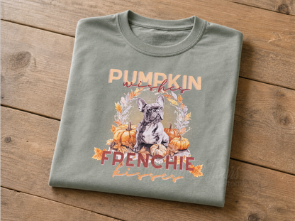 A folded sage green t-shirt with a graphic featuring a French Bulldog, displayed on a rustic wooden background.